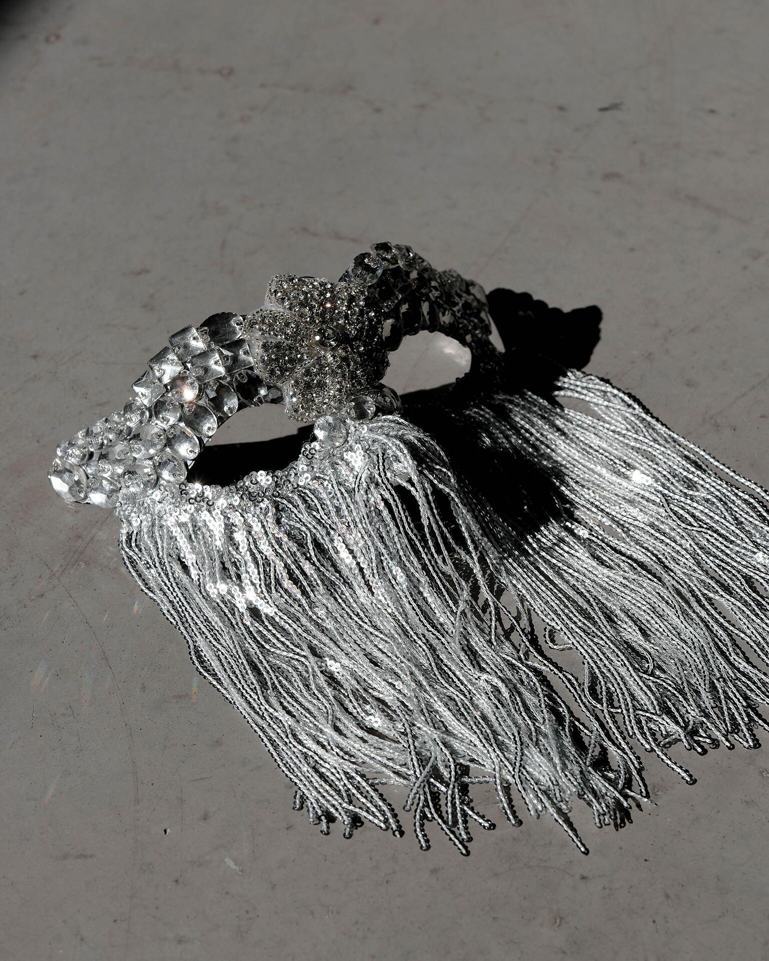 Silver mask with stones and hanging threads: Beyond