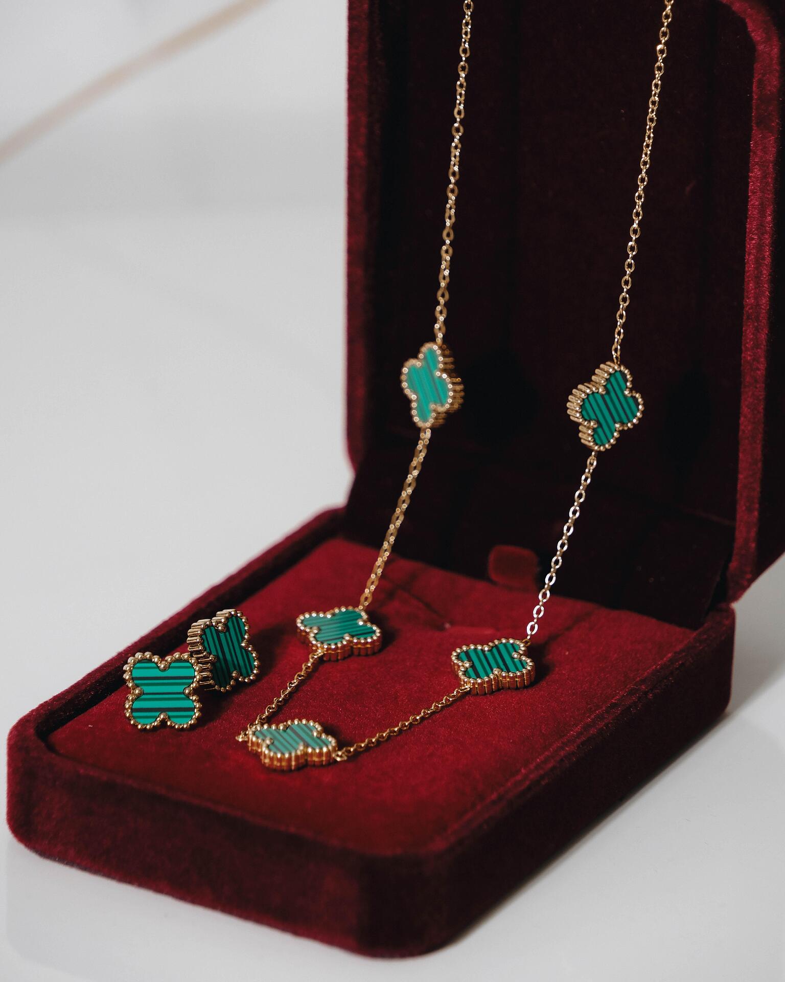 Gold necklace and earrings set with green clovers