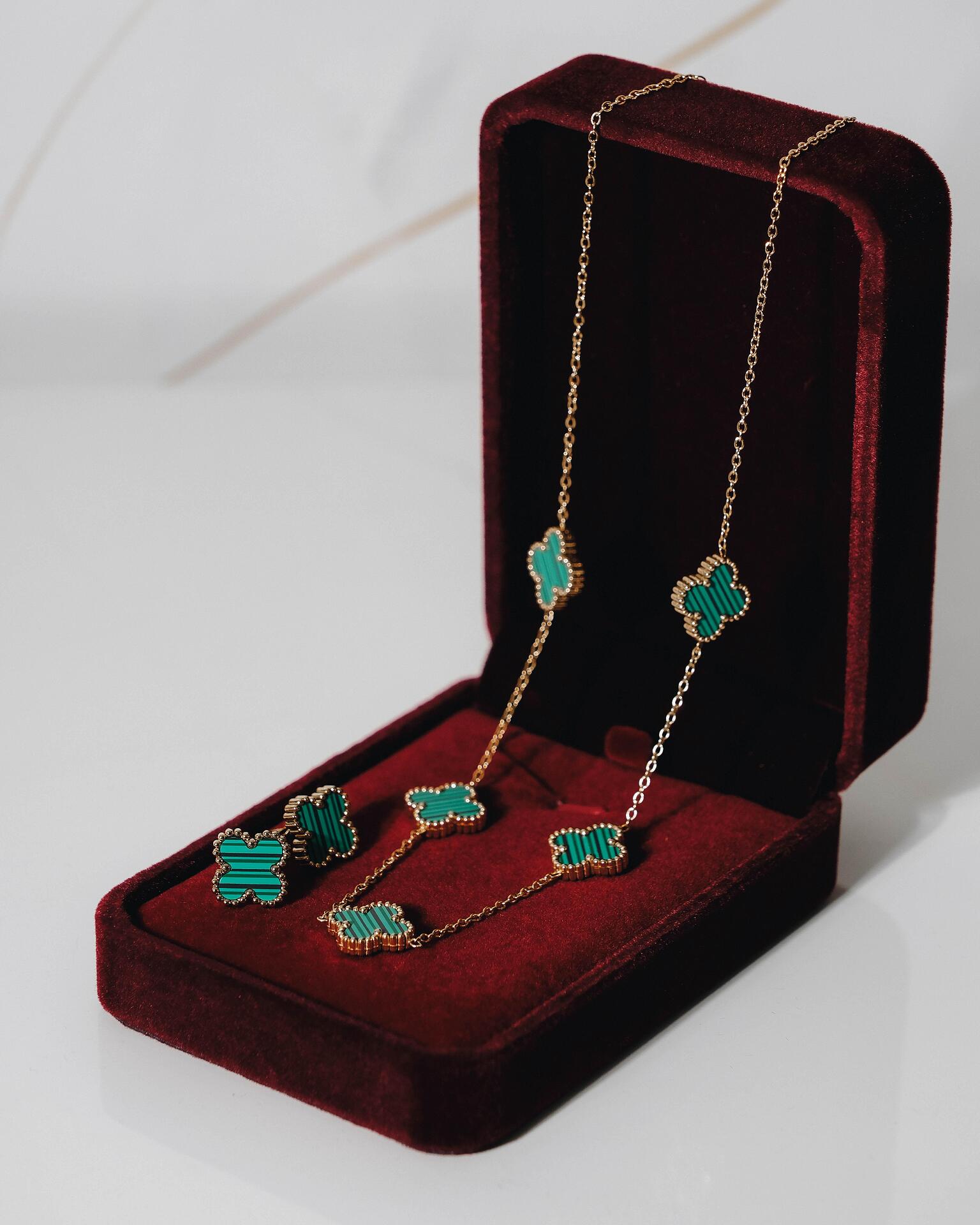 Gold necklace and earrings set with green clovers